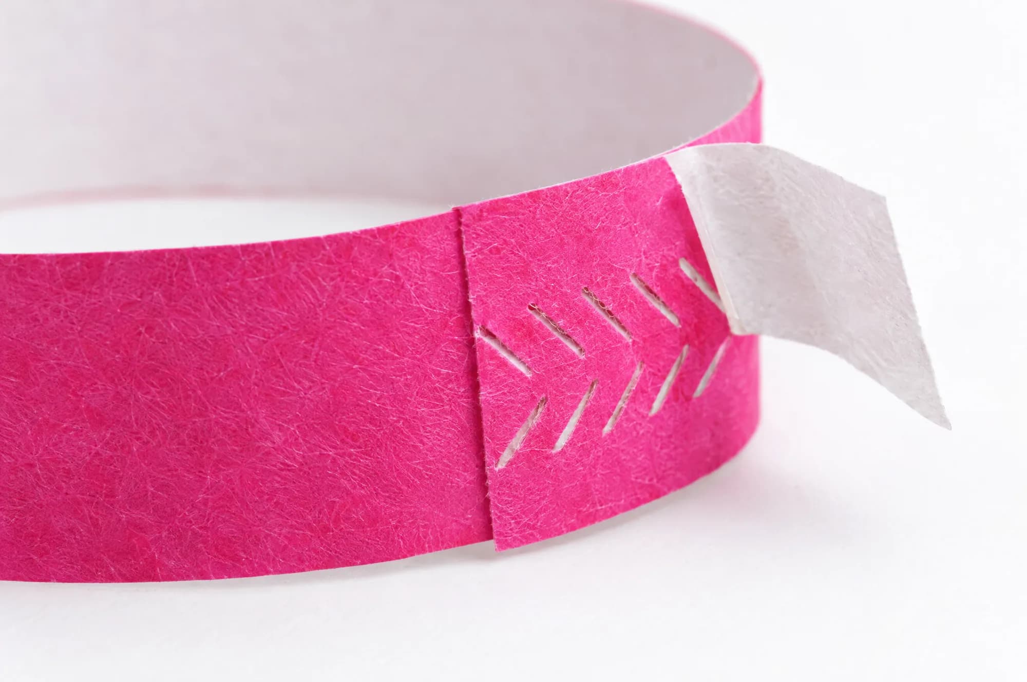 The adhesive end of a pink paper wristband with its liner peeled back